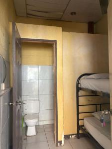 a bathroom with a toilet in a room with bunk beds at Hostal Los Cheles in León