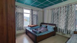 a bedroom with a bed and a window with curtains at Indu Homestay in Shimla