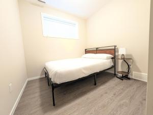 a bedroom with a bed with white sheets and a window at Villa Meadows Lethbridge in Lethbridge