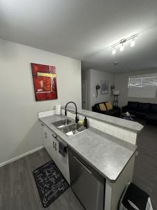 a kitchen with a sink and a living room at Villa Meadows Lethbridge in Lethbridge +10 photos