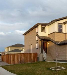 a house with a wooden fence in front of it at Villa Meadows Lethbridge in Lethbridge