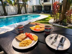a table with two plates of breakfast food and a pool at CulturaHumana Guesthouse in Panama City