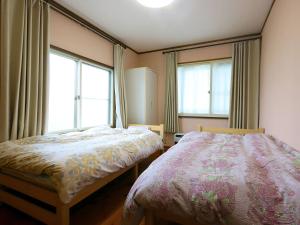 a bedroom with two beds and two windows at ゲストハウス ソウル in Azumino