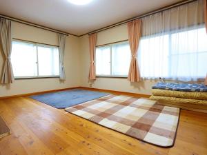 a room with a large rug on the floor with windows at ゲストハウス ソウル in Azumino