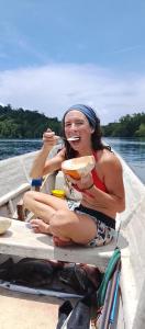 a woman sitting on a boat eating a hot dog at manyaifun guest house in Minyaifuin
