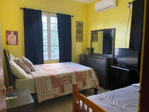a bedroom with a bed and a television and a dresser at Rincon Boricua Apartments in Rincon