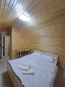 a large bed in a wooden room with a table at "AILUN" Issyk Kul in Tong