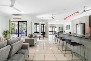 a living room with a couch and a bar with chairs at Zen Orient Luxurious 4BR Oasis with Private Pool in Leanyer