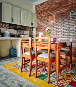 a kitchen with a wooden table with chairs and a brick wall at Sabi House Danu, Family Home near Prawirotaman in Timuran