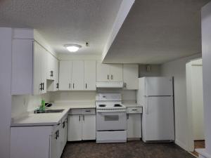 a kitchen with white cabinets and a white refrigerator at Executive Cozy 2bedroom Basement Suite in Brandon