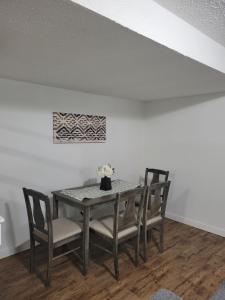 a dining room table with chairs and a painting on the wall at Executive Cozy 2bedroom Basement Suite in Brandon