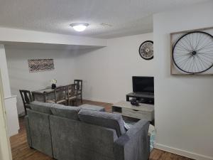 a living room with a couch and a table and a clock at Executive Cozy 2bedroom Basement Suite in Brandon