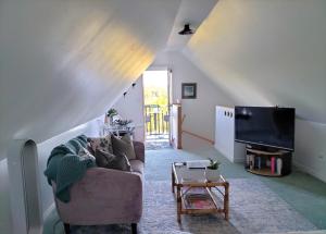 a living room with a couch and a tv at Cosy Orchard Loft - Fast WIFI in Tauranga