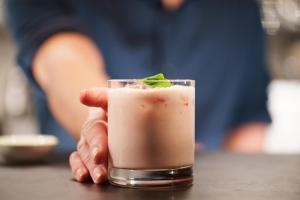 a person holding a drink with a green leaf on it at TONES Osaka in Osaka