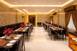 a row of tables in a restaurant with red flowers at Grand Maalyasa Hotel and Suites, US Consulate Hyderabad 2 Mins walk in Hyderabad