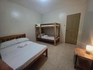 a bedroom with a bed and a bunk bed with a table at Teena Verde in Puerto Princesa City