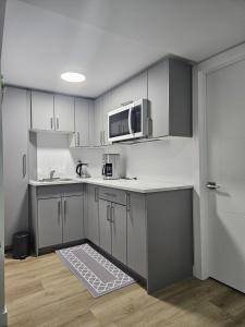 a kitchen with white cabinets and a microwave at Transcona Stay in Winnipeg