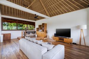 a living room with a couch and a flat screen tv at Villa Fafa by BaliSuperHost in Ubud