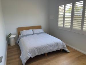 a white bedroom with a bed and a window at Silver Sands Villa in Mandurah