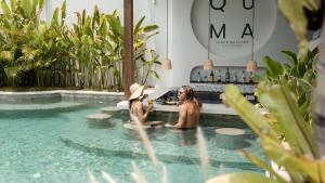 two women sitting in the pool at a bar in a swimming pool at Quma Boutique Hotel - Adults Only in Gili Trawangan