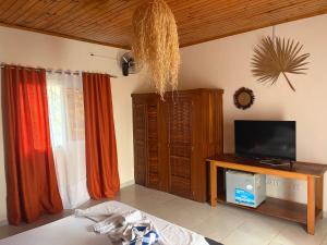 a living room with a flat screen tv and curtains at Villa Baby lodge in Hell-Ville