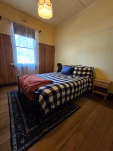 a bedroom with a bed with a checkered blanket at The Caramut Hotel in Caramut