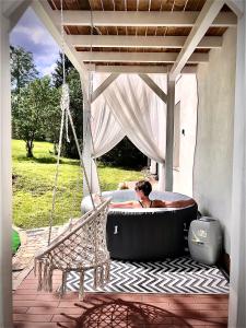 a man in a bath tub on a patio at Kino na łące apartament z jacuzzi i prywatną salą kinową in Wojcieszyce