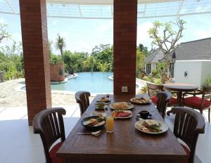 a wooden table with plates of food on a patio at Sardja Uluwatu in Uluwatu