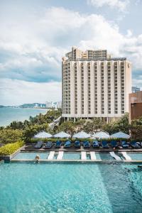 a pool with chairs and umbrellas in front of a hotel at Sheraton Nha Trang Hotel & Spa in Nha Trang