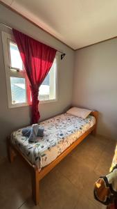 a small bedroom with a bed with a red curtain at Hostel Acuarelas in El Chalten
