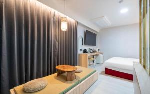 a bedroom with a bed and a table with a stool at H Avenue Hotel Gyeryong Eomsa branch in Gyeryong
