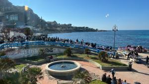 a group of people walking around a fountain by the water at Suite del Corso in Ficarazzi