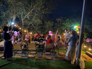 a group of people sitting in chairs at a party at night at Nhà Bên Suối Retreat in Làng Tè