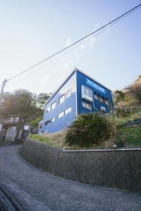 a blue building on the side of a road at Guesthouse All you need - All rooms have an ocean view! in Shimoda