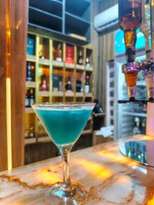 a blue drink in a martini glass sitting on a bar at Fairtex Luxury Hotels in Maiyegun
