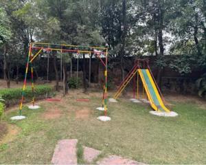 a playground with two swings in a park at Aaliya Farm House in Dhauj +1 photo