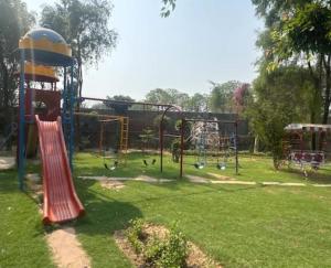 a park with a playground with a slide and swings at Aaliya Farm House in Dhauj