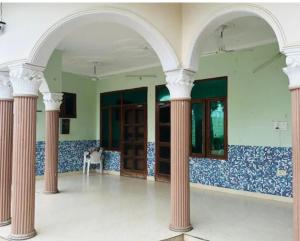 an empty room with columns and windows in a building at Aaliya Farm House in Dhauj