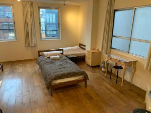 a bedroom with a bed and a desk and windows at ホテル スミヨシホルモン in Tokyo