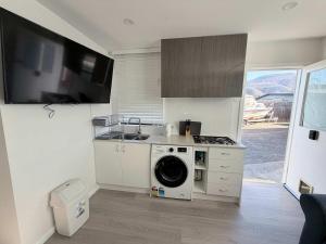 a kitchen with a sink and a washing machine at Claremont Comfort Cottage in Claremont
