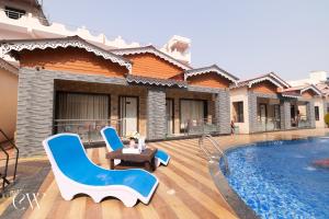 a villa with a swimming pool and two blue chairs at Rath Inns Beach Resort Mandarmani in Mandarmoni