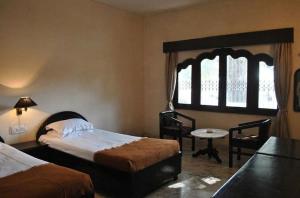 a bedroom with two beds and a table and a window at Hotel Marble Palace in Khajurāho