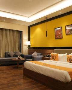 a hotel room with two beds and a couch at The Murti Hotel and Banquet in Noida