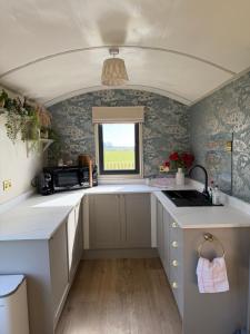 a small kitchen with white cabinets and a window at The Shepherds Chalet in Garstang