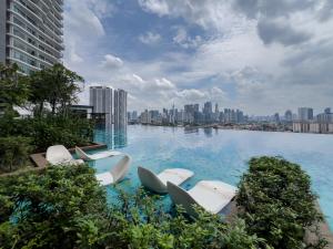 a swimming pool with white chairs in the middle of a city at Luxury Condo Datum Jelatek Near KLCC,free Parking in Kampong Datok Keramat
