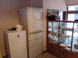 a kitchen with a refrigerator and a shelf with dishes at HOTEL Saboten Apartment in Miyoshi