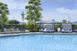 a pool with chairs and umbrellas at Hyatt Regency Los Angeles International Airport in Los Angeles