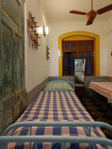 a bedroom with two beds and a ceiling fan at Hostel Vasantashram CST Mumbai, Free Wifi with 1940s Retro vibe in Mumbai