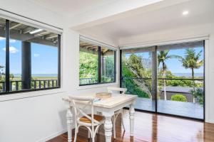 a white dining room with windows and a table and chairs at Ocean Outlook Retreat in River Heads