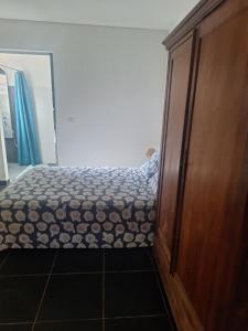 a bedroom with a bed and a wooden cabinet at L' ecrin de douceur in Saint-Benoît +2 photos